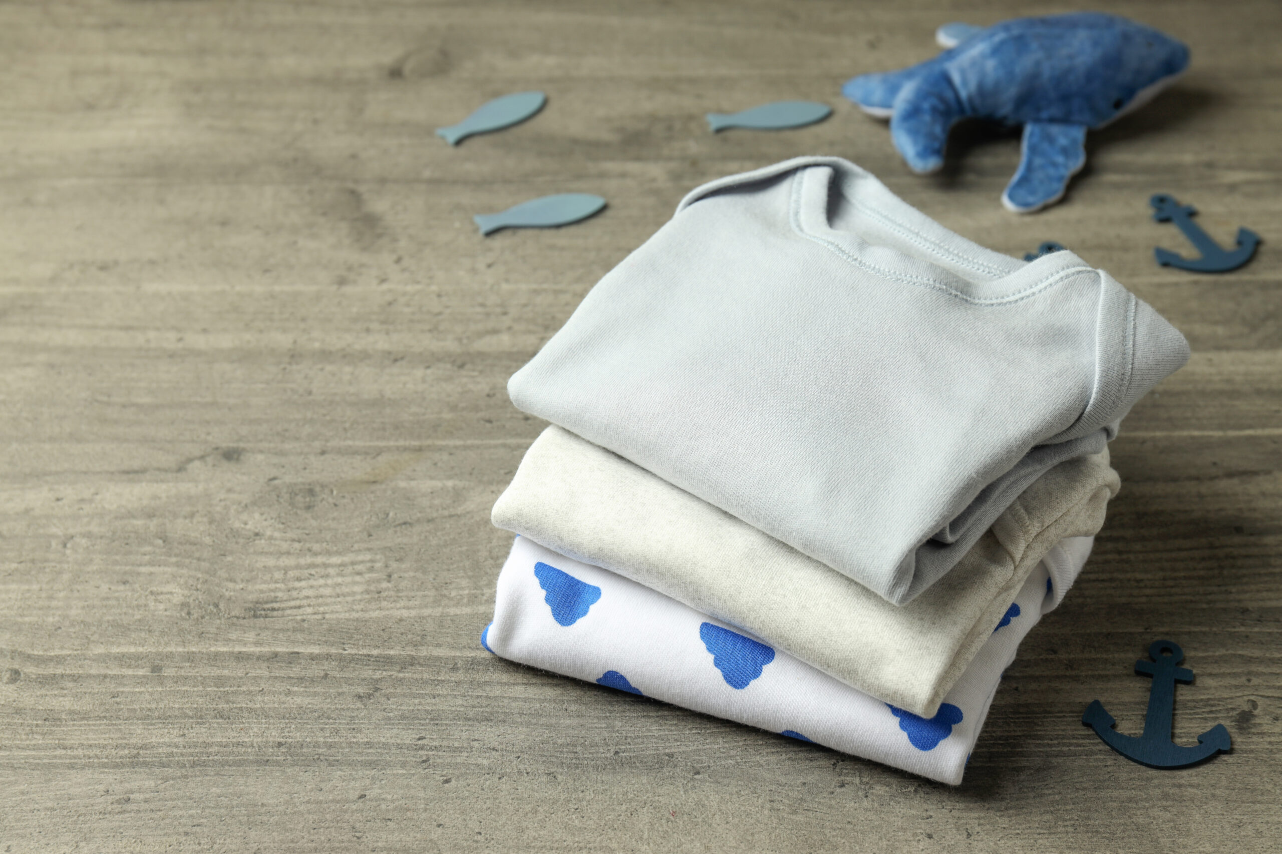 Concept of cute baby clothes on gray textured background.
