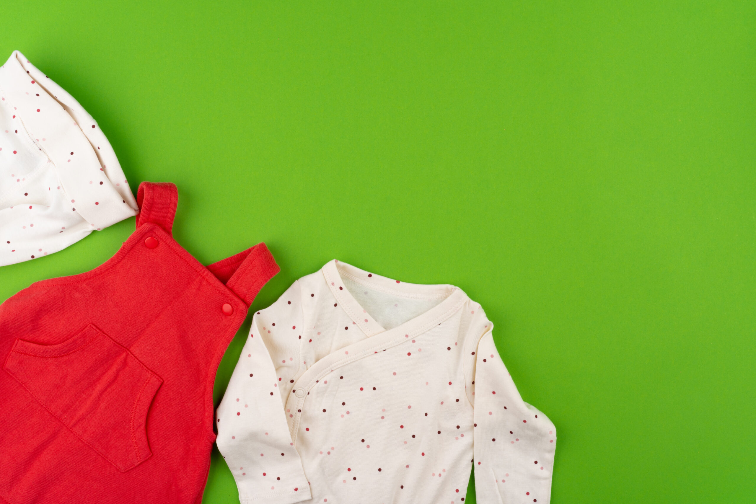 Top view of baby clothes on green background