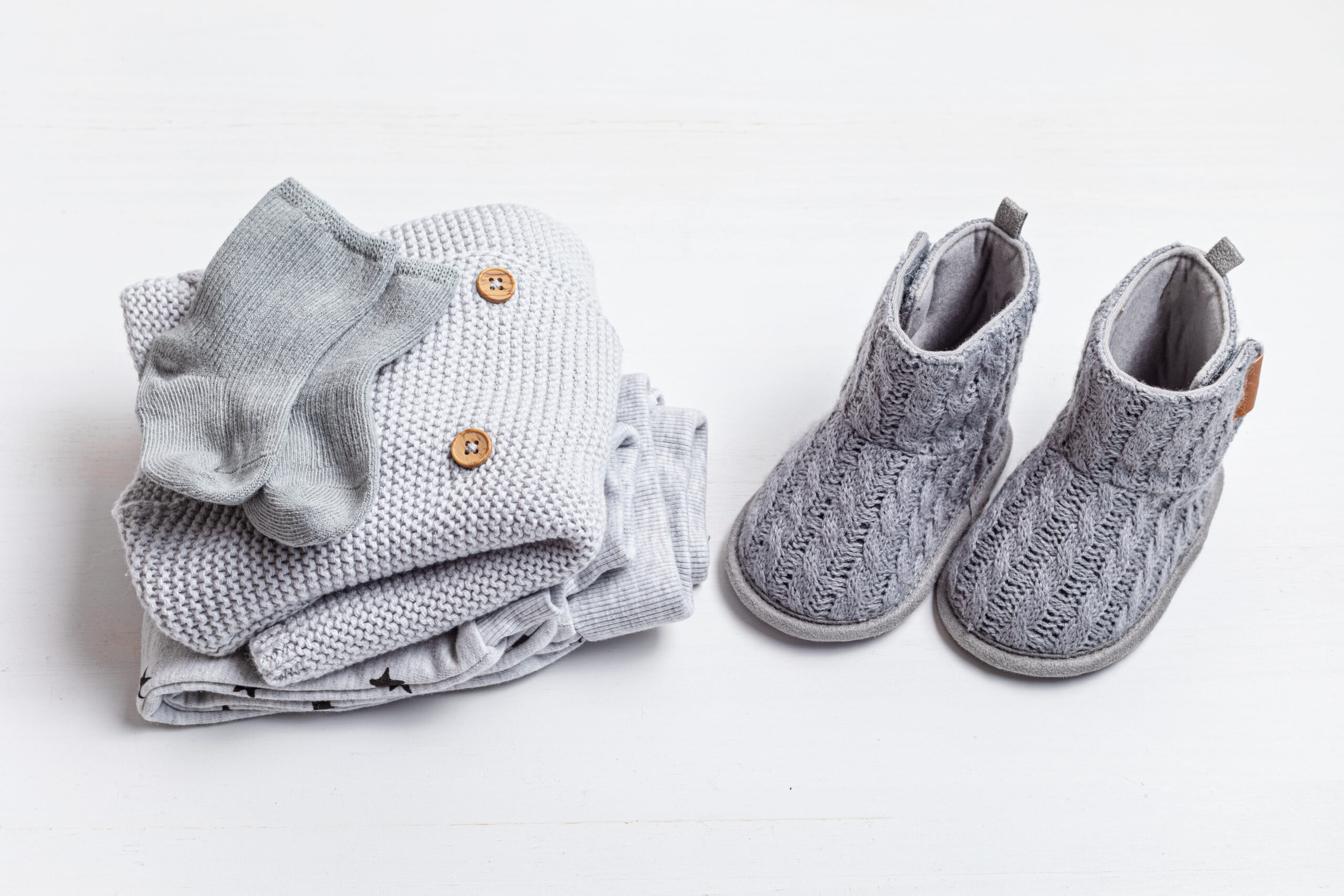 Collection of cute organic  baby clothes and booties. Warm gender neutral outfit for cold weather of fall and winter season. Newborn gifts, baby shower, second hand clothes, donation idea.